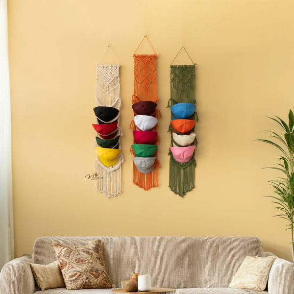 Three colorful wall hangings with pots on a yellow wall above a sofa.