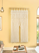 Macrame wall hanging in a living room with a yellow wall and wooden coffee table.