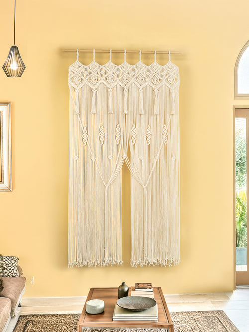 Macrame wall hanging in a living room with a yellow wall and wooden coffee table.