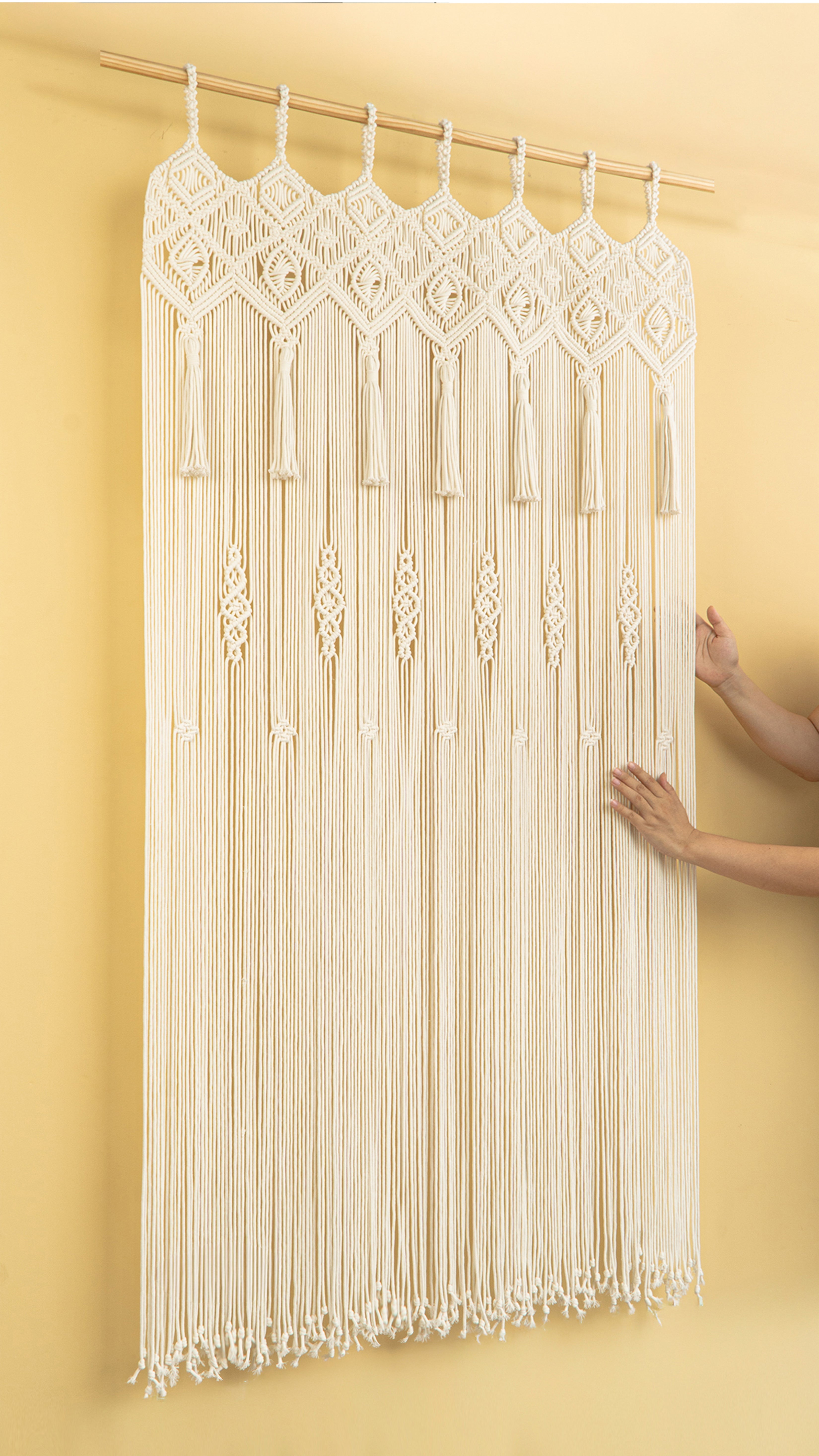 Macrame wall hanging with tassels on a yellow background