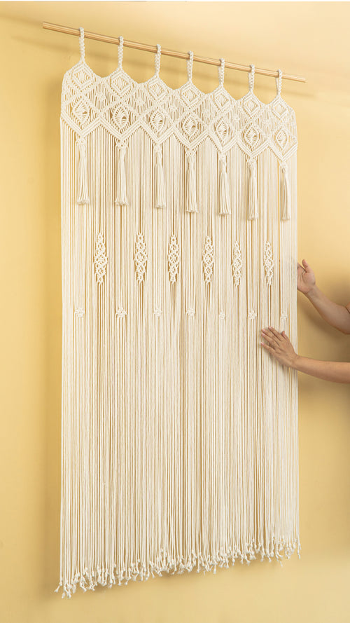Macrame wall hanging with tassels on a yellow background