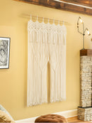 Macrame wall hanging in a room with a lamp and framed picture on the wall.