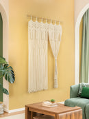 Macrame wall hanging on a yellow wall with a green sofa and wooden coffee table.