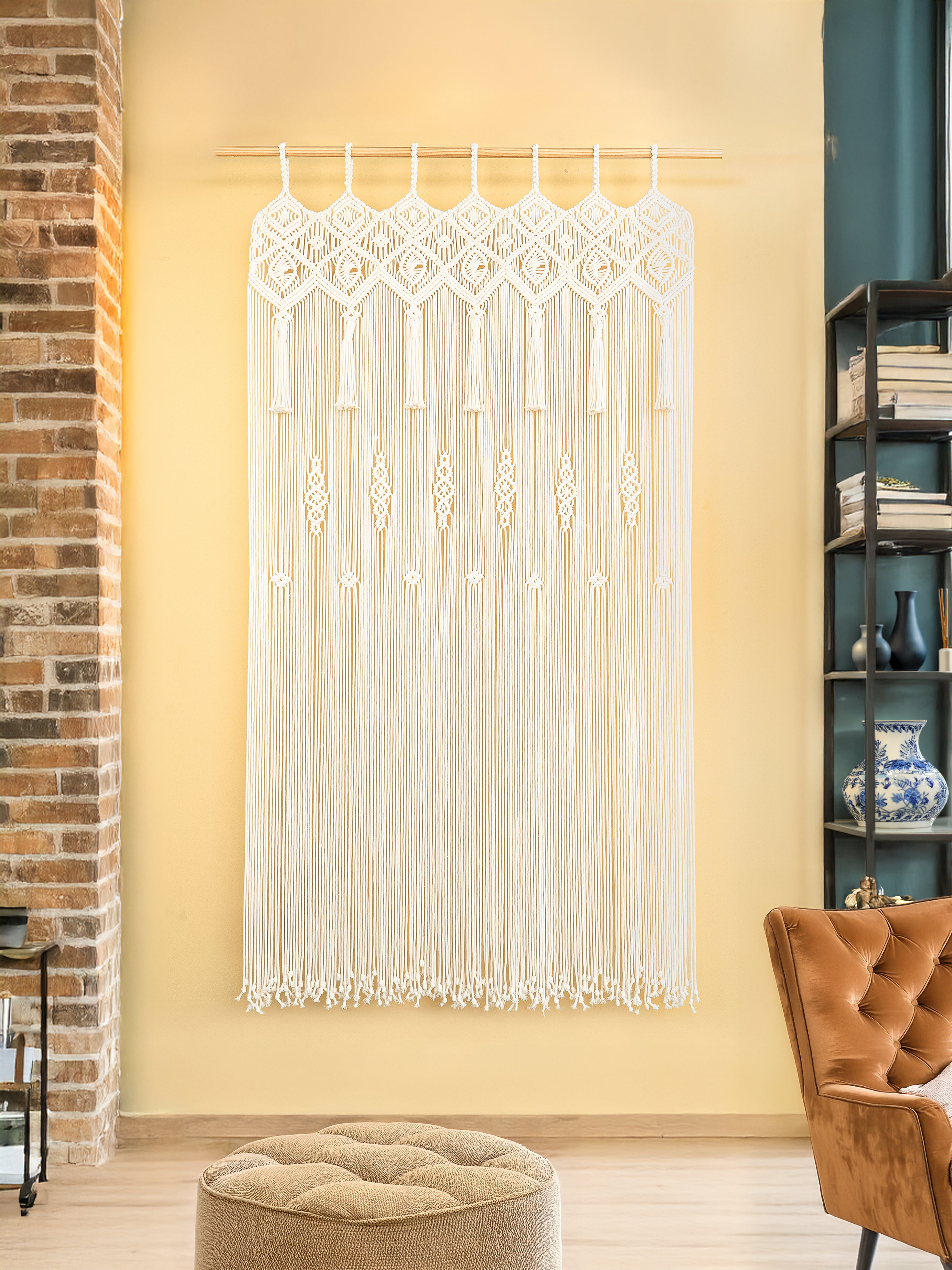 Decorative string curtain hanging in a room with a brick wall and bookshelf.
