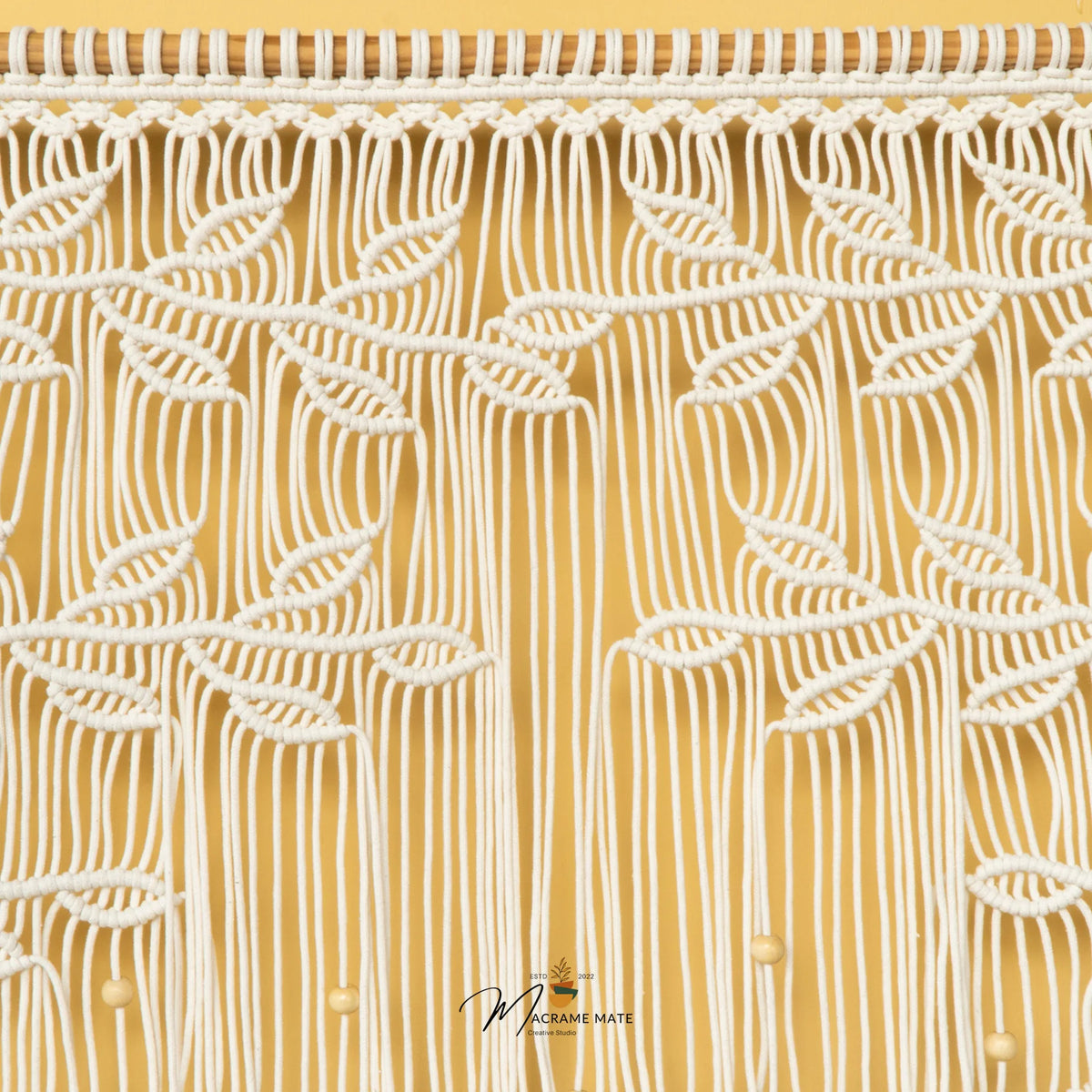 A close-up of a textured fabric or wallpaper featuring a stylized tree design with orange-brown branches and leaves on a warm beige background, accented with small white beads.