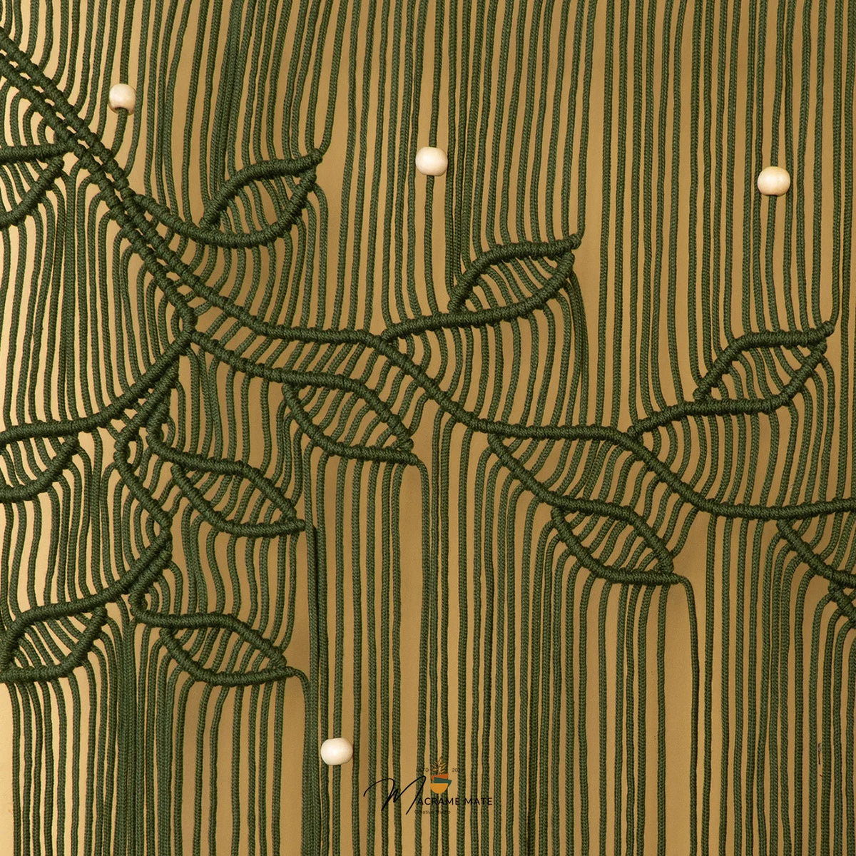 A close-up of a textured wall or wallpaper featuring a dark green rope-style leaf and vine pattern over a warm tan background with vertical ribbed lines and small white bead accents.