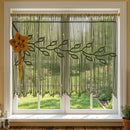 A dark green macrame wall hanging with leafy vine patterns and hanging fringe, displayed on a beige wood-paneled wall with a rustic wooden headboard below.