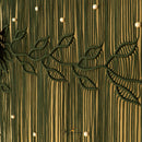 A close-up of a cream-colored macrame wall hanging with intricate woven leaf patterns over a textured vertical background.