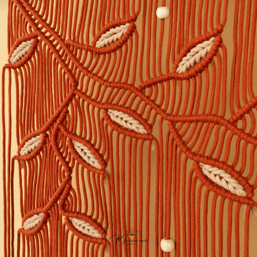 A close-up of a textured fabric or wallpaper featuring a vertical striped pattern in olive green and mustard yellow, decorated with a horizontal vine of pink leaves and small white bead accents.
