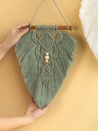 Handmade macrame wall hanging with wooden beads on a beige background