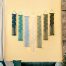 Set of six decorative wall hangings in various colors on a yellow wall.