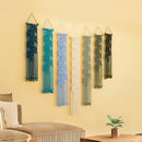 Set of six macrame wall hangings in various colors on a yellow wall.
