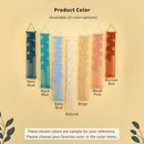A product color selection graphic showing six macrame wall hangings in different colors: Navy Blue, Aqua Blue, Baby Blue, Beige, Blush Pink, and Maroon Red, labeled 'Product Color' with 'Available 25 color options' above. The background is a warm beige with decorative leaf silhouettes at the bottom corners and a note at the bottom stating the shown colors are sample colors and to choose from the color menu.