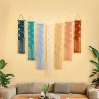 Colorful macrame wall hangings on a yellow wall above a sofa.