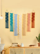 Colorful woven wall hangings on a yellow wall with a wooden cabinet below.