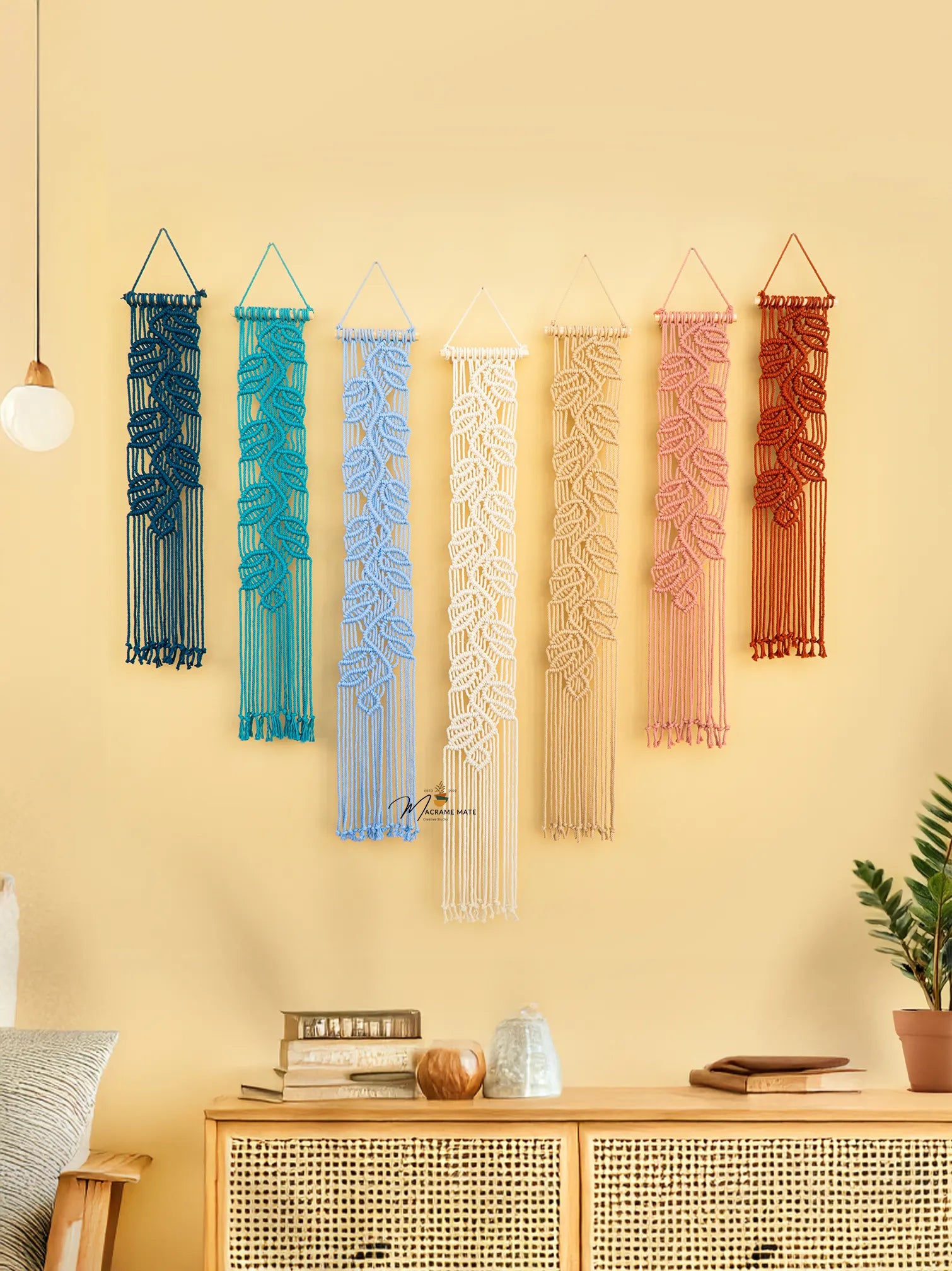 Colorful woven wall hangings on a yellow wall with a wooden cabinet below.