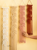 Four macrame wall hangings in different colors on a yellow background.
