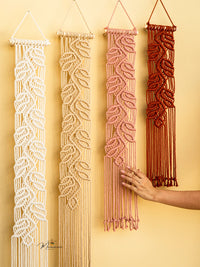 Four macrame wall hangings in different colors on a yellow background.