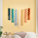 Set of colorful macrame wall hangings on a yellow wall with a modern interior setting.