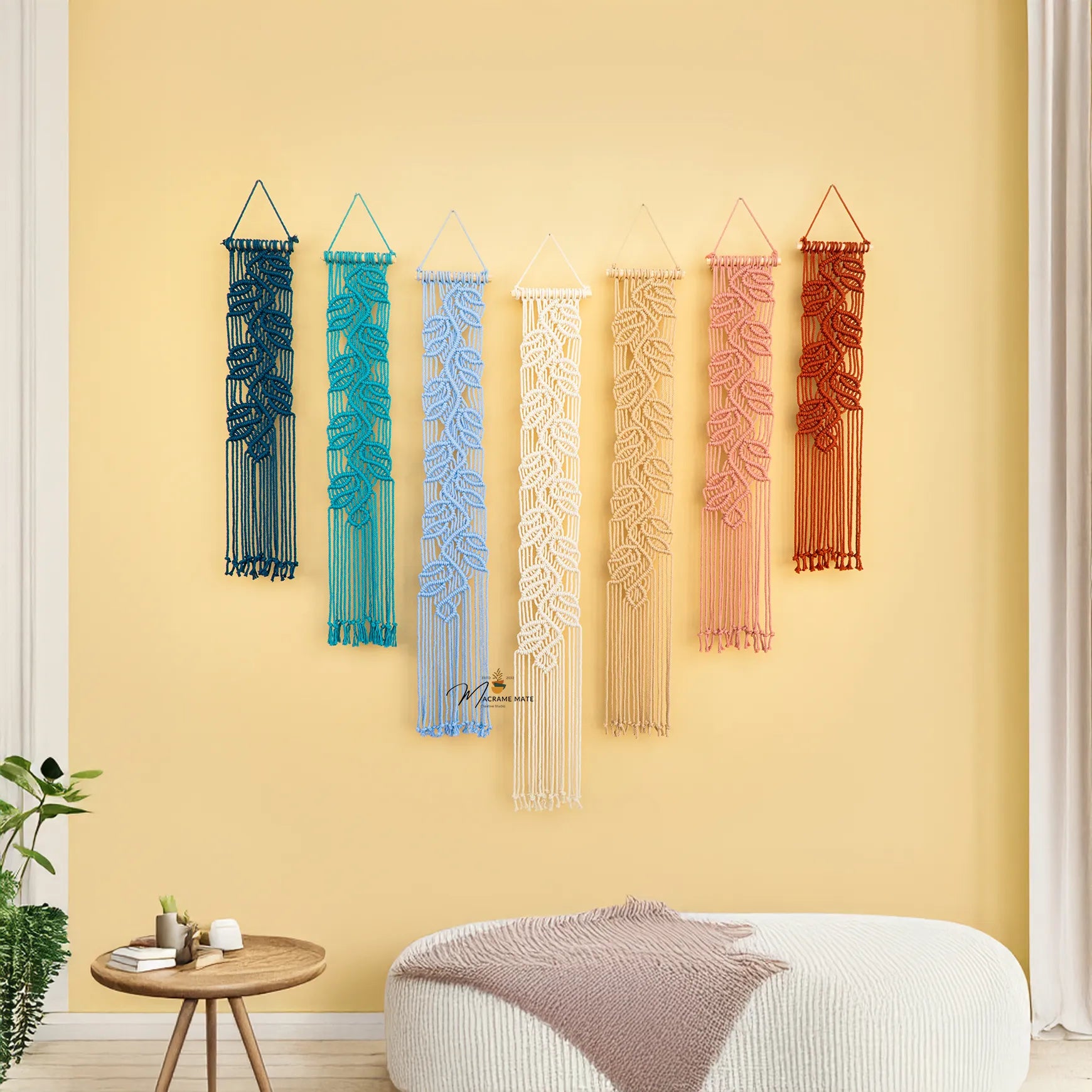 Set of colorful macrame wall hangings on a yellow wall with a modern interior setting.