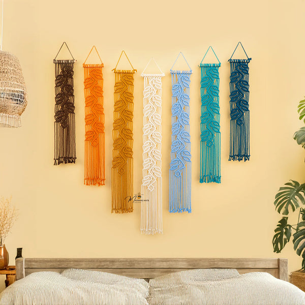 Set of colorful wall hangings on a beige wall above a bed.