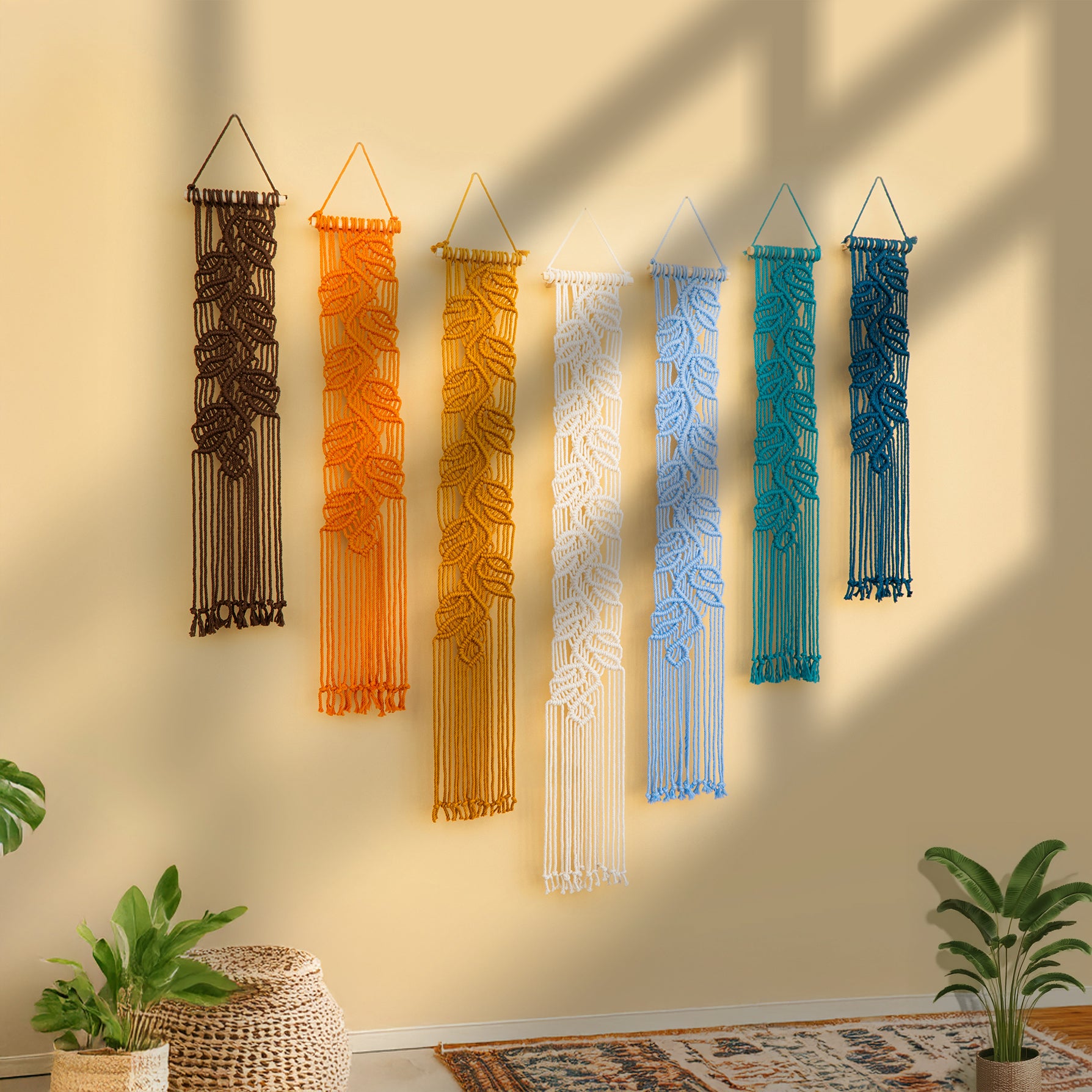 Set of colorful wall hangings on a beige wall with plants and a rug in the foreground.