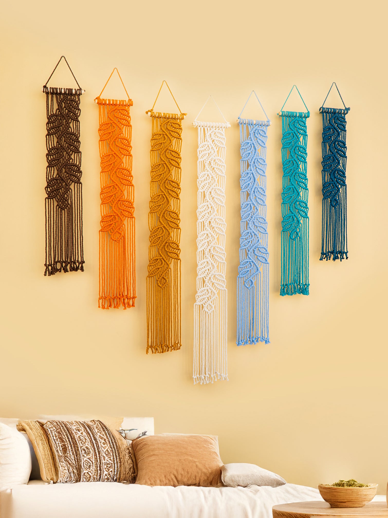 Angled view of colorful vertical macrame wall hangings in a boho bedroom wall