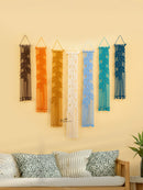 Set of colorful wall hangings on a beige wall above a sofa with decorative pillows.
