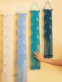 Four macrame wall hangings in different colors on a yellow background