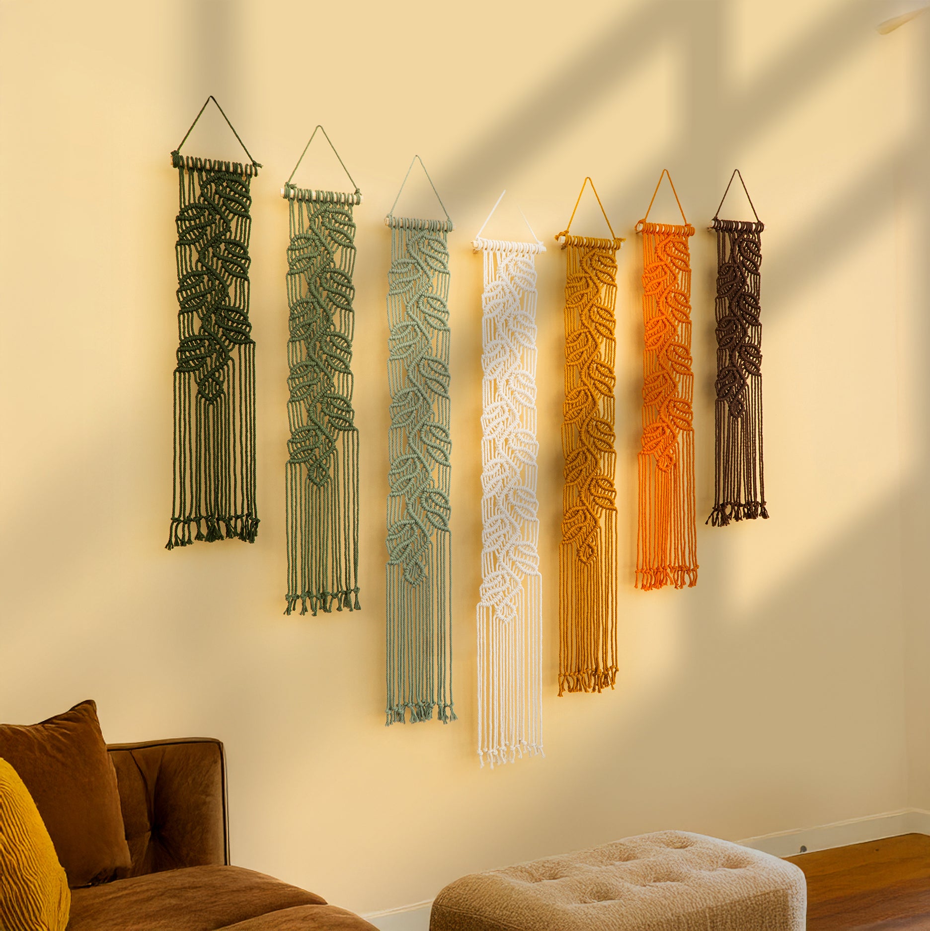 Set of six string art wall hangings in various colors on a beige wall.