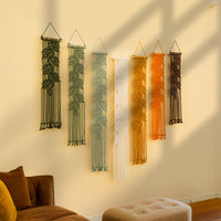 Set of six string art wall hangings in various colors on a beige wall.