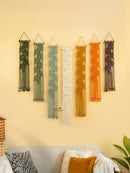 Set of colorful wall hangings on a yellow wall above a sofa.