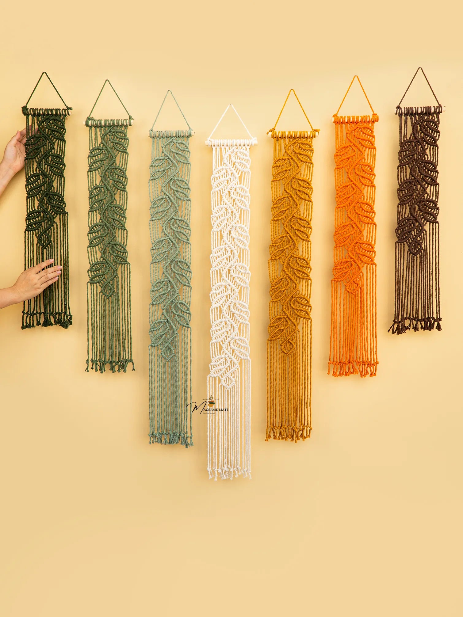 Set of six woven wall art pieces in various colors on a beige background
