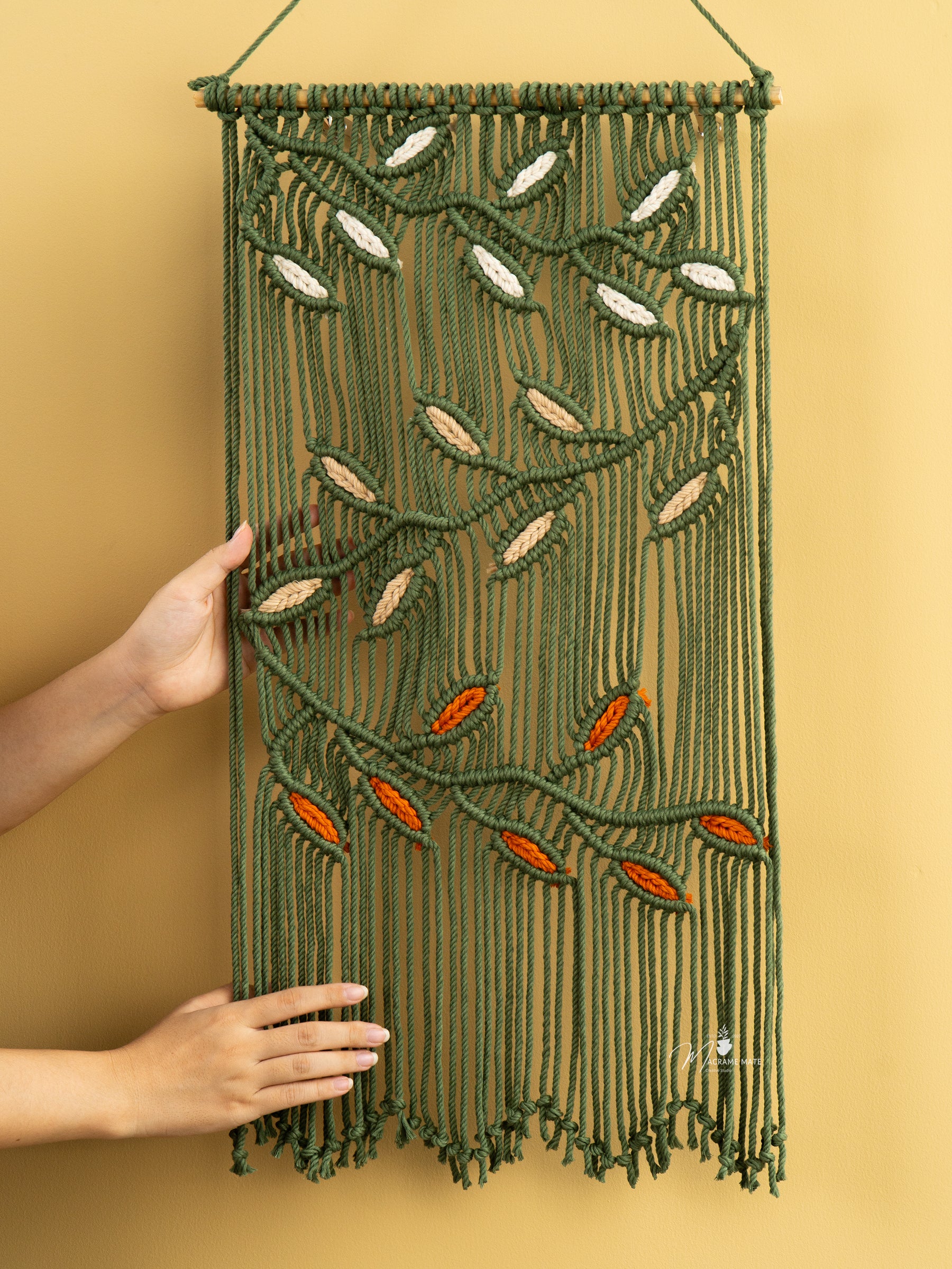 Macrame wall hanging with leaf patterns on a yellow background