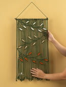 Handmade wall hanging with embroidered leaves on a yellow background
