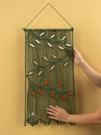 Handmade wall hanging with embroidered leaves on a yellow background