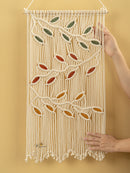 Macrame wall hanging with leaf patterns on a yellow background