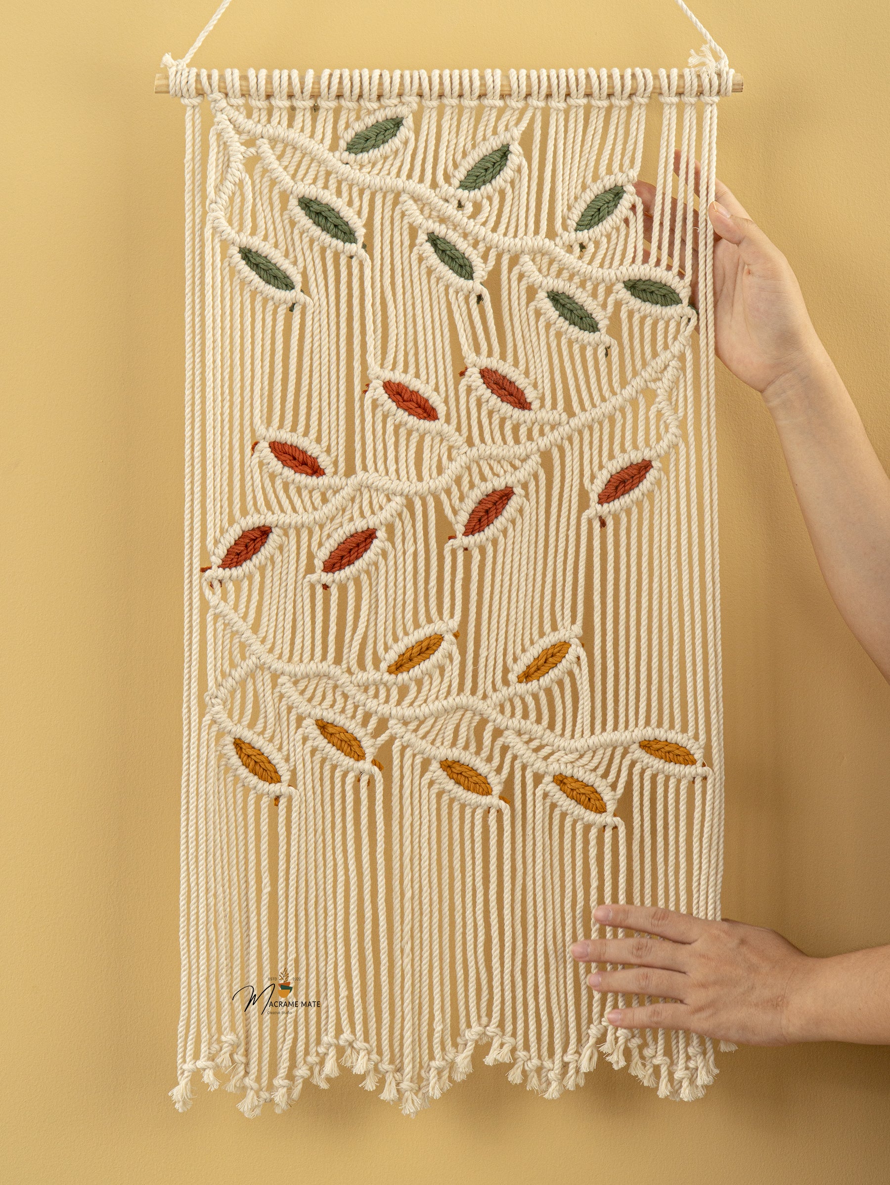 Macrame wall hanging with leaf patterns on a yellow background