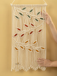 Macrame wall hanging with leaf patterns on a yellow background