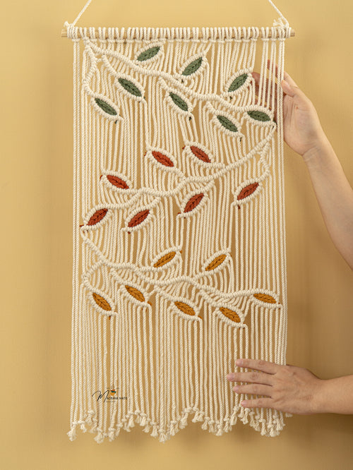 Macrame wall hanging with leaf patterns on a yellow background