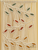 Macrame wall hanging with leaf patterns on a beige background