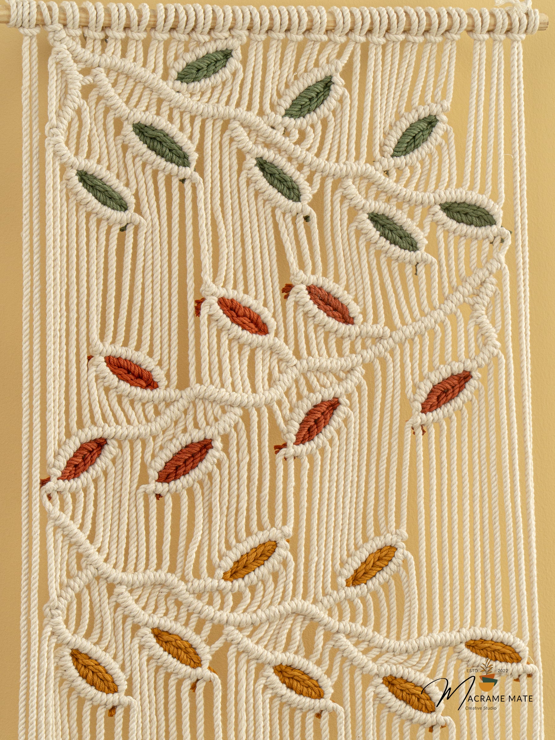 Macrame wall hanging with leaf patterns on a beige background