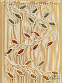 Macrame wall hanging with leaf patterns on a beige background