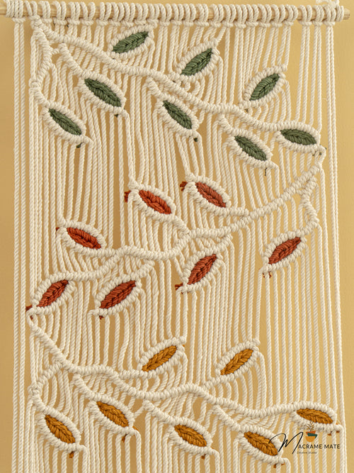 Macrame wall hanging with leaf patterns on a beige background