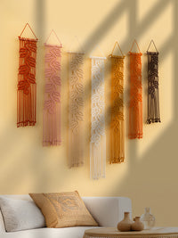Set of six woven wall hangings in various colors on a beige wall above a sofa.