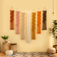Set of five macrame wall hangings in various colors on a beige wall.