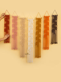 Set of macrame wall hangings in various colors on a beige background