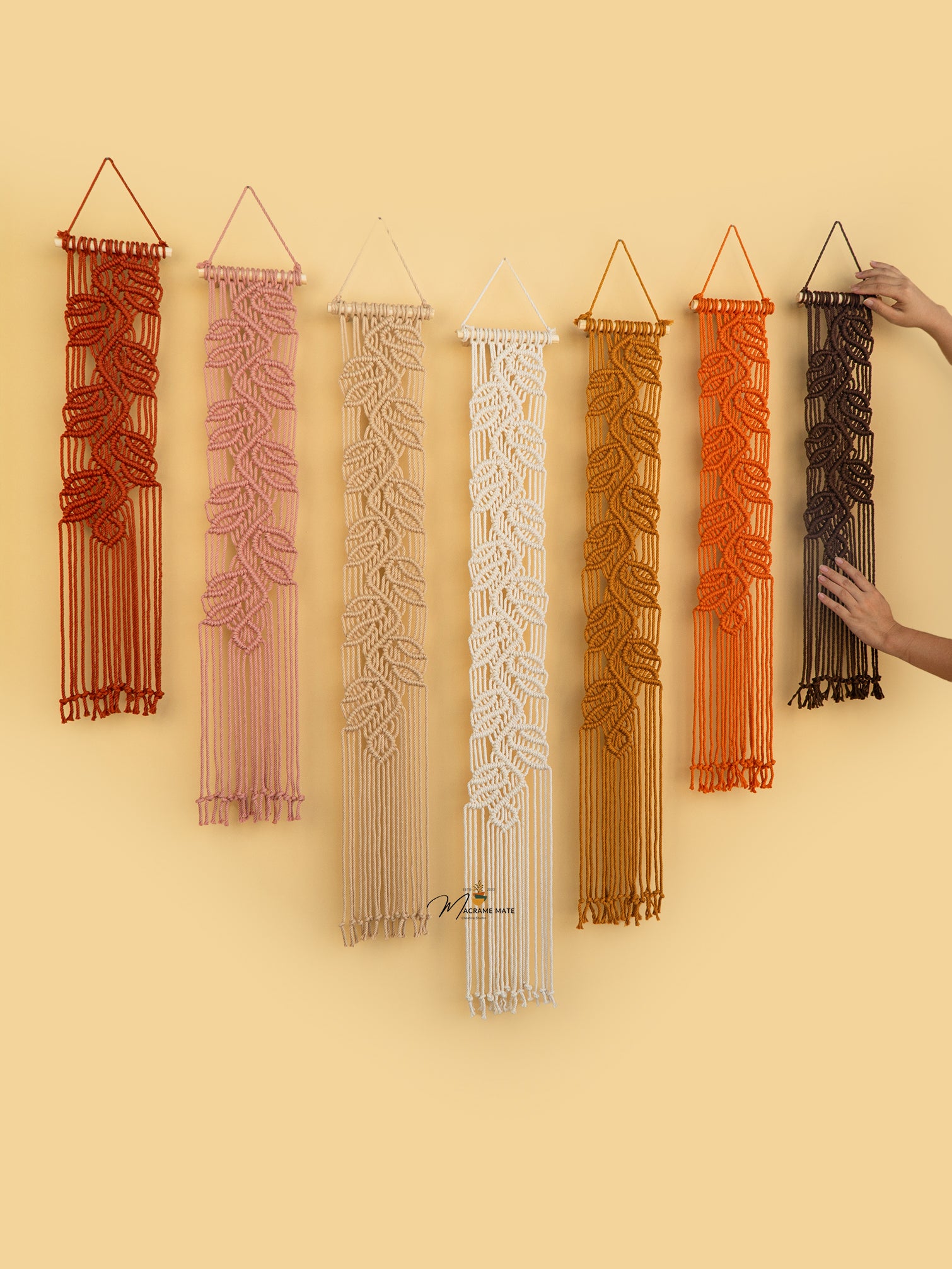 Set of six macrame wall hangings in various colors on a yellow background.