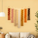 Set of five wall hangings in various colors on a yellow wall above a sofa.