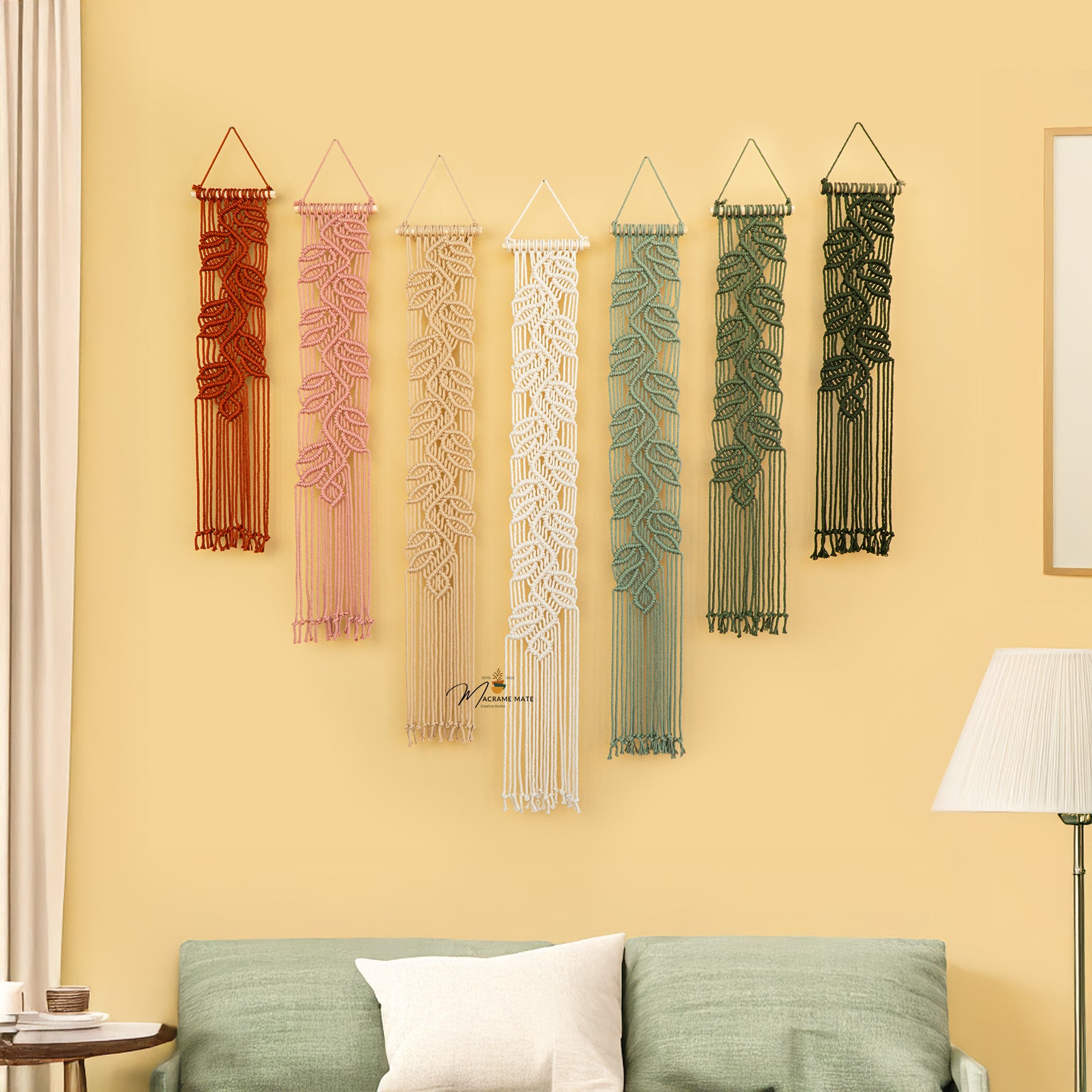 Set of six decorative wall hangings with leaf patterns on a yellow wall.